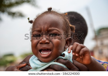 PORTO-NOVO, BENIN - MAR 10, 2012: Unidentified Beninese man hols his little crying girl scared of camera. People of Benin suffer of poverty due to the difficult economic situation