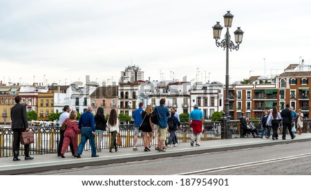 SEVILLE, SPAIN - APR 14, 2014: Unidentified people walk over the Triana Bridge over the Guadalquivir river, Seville, Andalusia, Spain. It\'s the fifth longest river in the Iberian peninsula