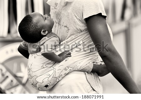 ACCRA, GHANA - MAR 5, 2012: Unidentified Ghanaian little boy sleeps on his mother back. People of Ghana suffer of poverty due to the difficult economic situation