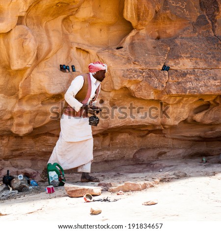WADI RUM, JORDAN - APR 30, 2014: Unidentified bedouin makes tea near the rock in the desert of Wadi Rum. Bedouins are a part of a desert-dwelling Arabian ethnic group
