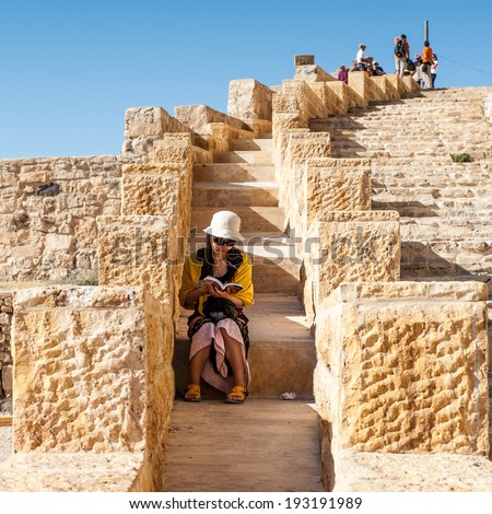 KERAK, JORDAN - APR 28, 2014: Unidentified girl reads a guide book on the stairs of the  Kerak Castle. Kerak Castle is a large crusader castle in Kerak (Al Karak) in Jordan.