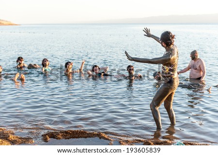 DEAD SEA RESORT, JORDAN - APR 30, 2014: Unidentified Chinese people in the mud of the Dead Sea. Dead Sea mud posesses the medical qualities and helps to the people with skin problems
