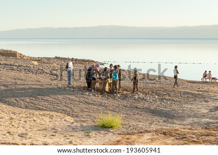 DEAD SEA RESORT, JORDAN - APR 30, 2014: Unidentified people put mud on their bodies. Dead Sea mud posesses the medical qualities