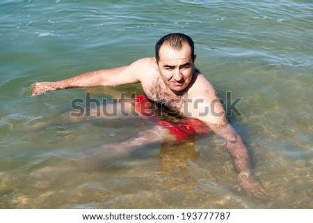 DEAD SEA RESORT, JORDAN - MAY 1, 2014: Unidentified man swims on the salty water of the Dead Sea. Dead Sea water is used for medical purposes for the people with skin problems