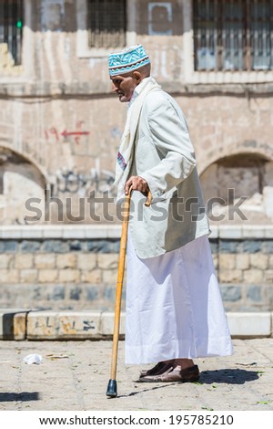 SANA\'A, YEMEN - JAN 11, 2014: Unidentified Yemeni old man walks with a stick in the street. People of Yemen suffer of poverty due to the unstable political and poor economical situation