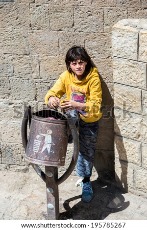 SANA'A, YEMEN - JAN 11, 2014: Unidentified Yemeni little girl near the trash box in the street in Sana'a. Children of Yemen grow up without education