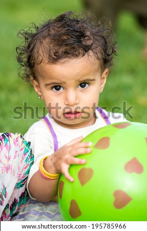 SANA\'A, YEMEN - JAN 11, 2014: Unidentified Yemeni little girl plays with a green rubber ball girl in the street in Sana\'a. Children of Yemen grow up without education