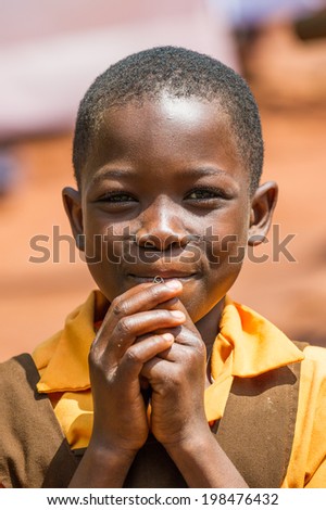 ACCRA, GHANA - MARCH 5, 2012: Unidentified Ghanaian boy in a yellow shirt smiles in the street in Ghana. Children of Ghana suffer of poverty due to the unstable economic situation