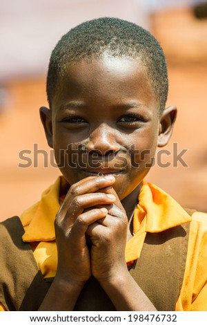 ACCRA, GHANA - MARCH 5, 2012: Unidentified Ghanaian boy in a yellow shirt smiles in the street in Ghana. Children of Ghana suffer of poverty due to the unstable economic situation