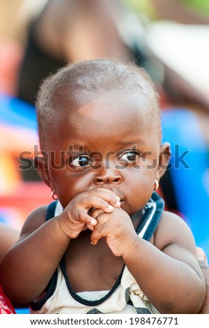 ACCRA, GHANA - MARCH 5, 2012: Unidentified Ghanaian boy on his mother lap in the street in Ghana. Children of Ghana suffer of poverty due to the unstable economic situation