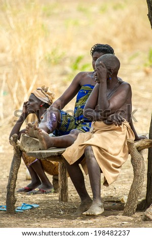 ACCRA, GHANA - MARCH 6, 2012: Unidentified Ghanaian ladies sit and talk on a bench in the street in Ghana. People of Ghana suffer of poverty due to the unstable economic situation
