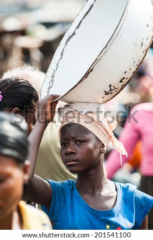 ACCRA, GHANA - MARCH 4, 2012: Unidentified Ghanaian woman trasports a pelvis over her head in Ghana. People of Ghana suffer of poverty due to the unstable economic situation