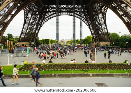 PARIS, FRANCE - JUN 17, 2014: Unidentified tourists walk near the Eiffel Tower in Paris, France. The Eiffel tower was created by Gustave Eiffel and the construction was completed in 1889