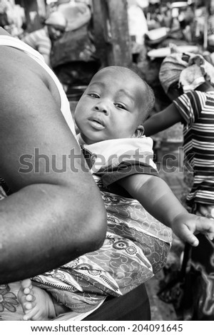 ACCARA, GHANA - MAR 3, 2012: Unidentified Ghanaian baby on the back of his mother  in black and white. People of Ghana suffer of poverty due to the unstable economical situation