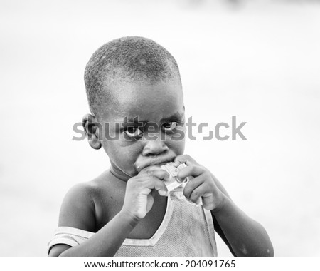 ACCARA, GHANA - MAR 2, 2012: Unidentified Ghanaian eating girl portrait in black and white. People of Ghana suffer of poverty due to the unstable economical situation