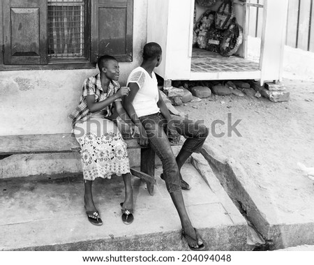 ACCARA, GHANA - MAR 2, 2012: Unidentified Ghanaian people sit in the street  in black and white. People of Ghana suffer of poverty due to the unstable economical situation