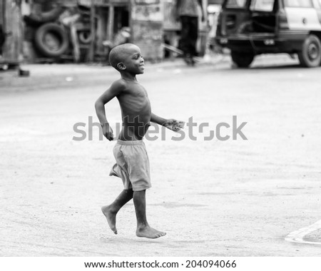ACCARA, GHANA - MAR 2, 2012: Unidentified Ghanaian boy runs in the street  in black and white. Children of Ghana suffer of poverty due to the unstable economical situation