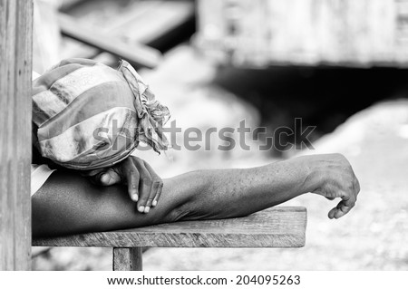 ACCARA, GHANA - MAR 2, 2012: Unidentified Ghanaian woman sleeps on a bench in the street in black and white. People of Ghana suffer of poverty due to the unstable economical situation