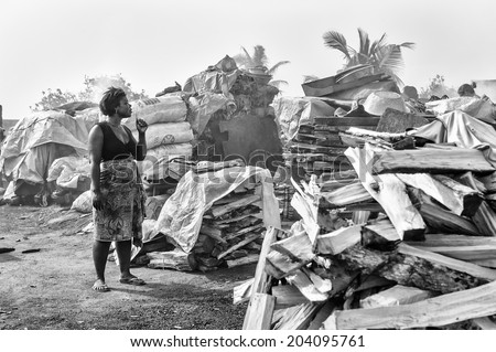 ACCARA, GHANA - MAR 6, 2012: Unidentified Ghanaian  woman stays near the bunch of wood in black and white. People of Ghana suffer of poverty due to the unstable economical situation