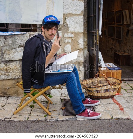 SAINT-PAUL-DE-VENCE, FRANCE - JUN 25, 2014: Unidentified painter draws in the street of Saint Paul de Vence, one of the oldest towns of the Frence Riviera. Town of painters and galleries