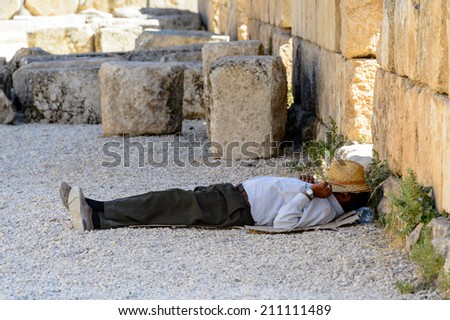 JERASH, JORDAN - MAY 2, 2014: Unidentified man takes a resr in the ancient city Gerasa, modern Jerash. Ancient Roman city of Gerasa reached a size of about 800,000 square meters within its walls.