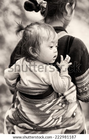 CATCAT VILLAGE, VIETMAN - SEP 12, 2014: Unidentified Vietnamese girl on her mother back in the Catcat village, Vietnam. 86% of Vietnamese people belong to the Viet ethnic group