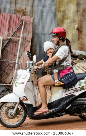 SIEM RIEP, CAMBODIA - SEP 28, 2014: Unidentified Khmer woman rides a motorbike with her little child in Siem Reap. 90% of Cambodian people belong to Khmer etnic group