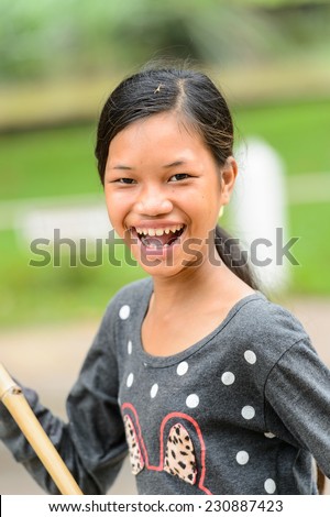 SIEM RIEP, CAMBODIA - SEP 28, 2014: Unidentified Khmer girl sweaps with a broom the ground  in Siem Reap. 90% of Cambodian people belong to Khmer etnic group