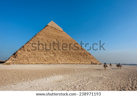 GIZA, EGYPT - NOV 23, 2014: Unidentified Egyptian people on camels caravan near the Great Pyramid in  Giza Necropolis, Egypt. UNESCO World Heritage