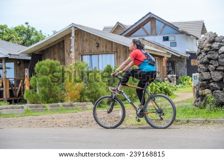 EASTER ISLAND, CHILE - NOV 10, 2014: Unidentified Chilean girl rides a bycicle on the Easter Island, Chile. Easter Island is a UNESCO World Heritage