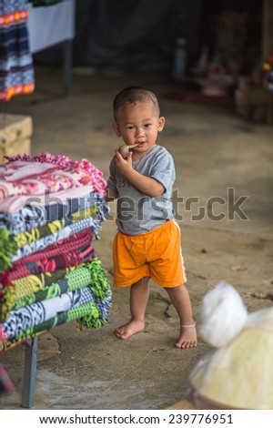 CATCAT, VIETMAN - SEP 20, 2014: Unidentified Hmong boy runs and put things in his mouth in Catcat village, Vietnam. Hmong is a minority ethnic group of Vietnam