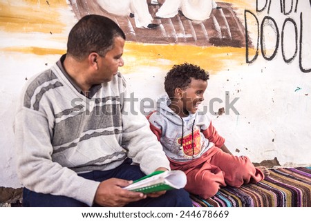 NUBIAN VILLAGE, EGYPT - DEC 2, 2014: Unidentified Nubian boy with an Egyptian man in a house. Nubian people settle along the banks of the Nile from northern Sudan to Aswan.