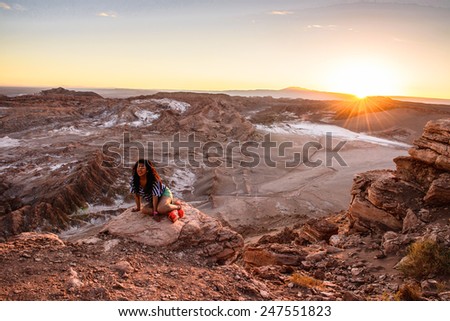 ATACAMA DESERT, CHILE - NOV 3, 2014: Unidentified girl sits on the sunset in the Atacama desert, Chile. Atacama Desert proper occupies 105,000 square kilometres