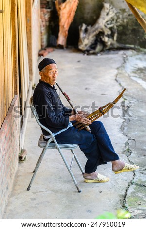 LAO CHAI VILLAGE, VIETNAM - SEP 22, 2014: Unidentified Hmong man plays a musical instrument in Lao Chai. Hmong is on of the minority eethnic group in Vietnam