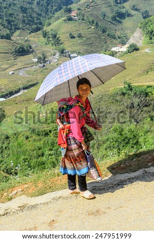 LAO CHAI VILLAGE, VIETNAM - SEP 22, 2014: Unidentified Hmong woman carries her little baby on her back in a village Lao Chai. Hmong is on of the minority ethnic group in Vietnam