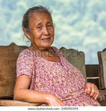 LUANG PRABANG, LAOS - SEP 25, 2014: Unidentified Lao woman sits on a bench bear the Mekong river. 55% of Laos people belong to the Lao ethnic group