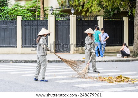 HANOI, VIETNAM - SEP 23, 2014: Unidentified Vietnamese woman cleans the street. 92% of Vietnamese people belong to the Viet ethnic group