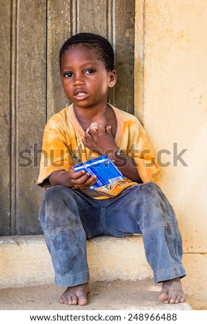 LOME, TOGO - MAR 9, 2013: Unidentified Togolese little boy sits at the porch of a house. People of Togo suffer of poverty due to the unstable economic situation.