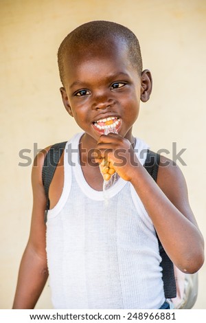 LOME, TOGO - MAR 9, 2013: Unidentified Togolese cute little boy smile, poses and eat candies. People of Togo suffer of poverty due to the unstable economic situation.