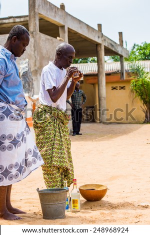 LOME, TOGO - MAR 9, 2013: Unidentified Togolese men in traditional clothes prepares a local drink. People of Togo suffer of poverty due to the unstable economic situation.