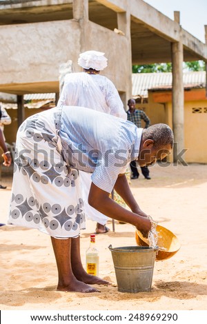 LOME, TOGO - MAR 9, 2013: Unidentified Togolese man in traditional clothes prepares a local drink. People of Togo suffer of poverty due to the unstable economic situation.