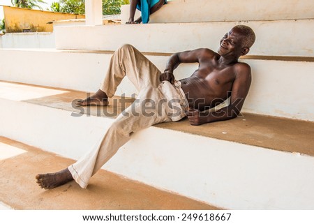 KARA, TOGO - MAR 9, 2013: Unidentified Togolese man in white pants smiles. People in Togo suffer of poverty due to the unstable econimic situation