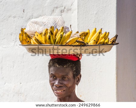 KARA, TOGO - MAR 9, 2013: Unidentified Togolese smiling woman carries a tray with bananas. People in Togo suffer of poverty due to the unstable econimic situation