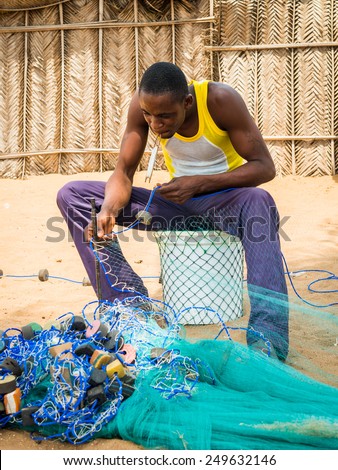 KARA, TOGO - MAR 9, 2013: Unidentified Togolese men sew the fish net for fishing. People in Togo suffer of poverty due to the unstable econimic situation