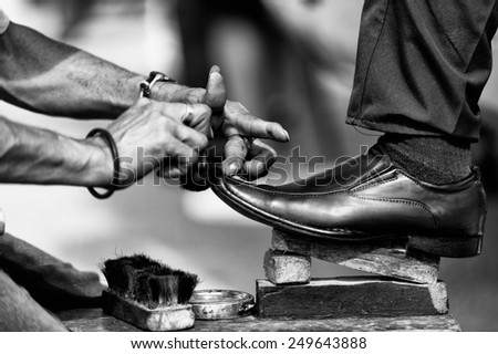 SAN JOSE, COSTA RICA - JAN 6, 2012: Unidentified Costa Rican man cleans shoes to the other man. 65.8% of Costa Rican people belong to the White (Castizo) ethnic group