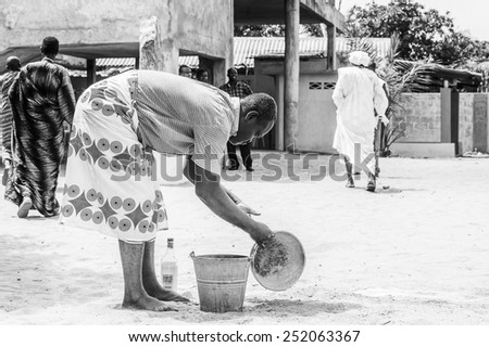 LOME, TOGO - MAR 9, 2013: Unidentified Togolese man in traditional clothes prepares a local drink. People of Togo suffer of poverty due to the unstable economic situation.