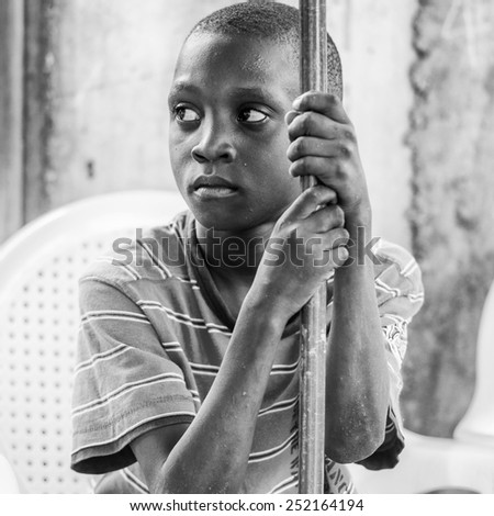 LOME, TOGO - MAR 9, 2013: Unidentified Togolese boy sits with sad eyes. People of Togo suffer of poverty due to the unstable economic situation.