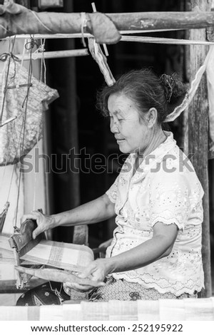 LUANG PRABANG, LAOS - SEP 25, 2014: Unidentified Lao woman sews outdoors. 55% of Laos people belong to the Lao ethnic group