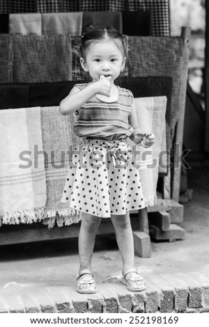 LUANG PRABANG, LAOS - SEP 25, 2014: Unidentified Lao little girl eats a candy. 55% of Laos people belong to the Lao ethnic group