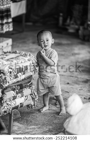 CATCAT, VIETMAN - SEP 20, 2014: Unidentified Hmong boy runs and put things in his mouth in Catcat village, Vietnam. Hmong is a minority ethnic group of Vietnam